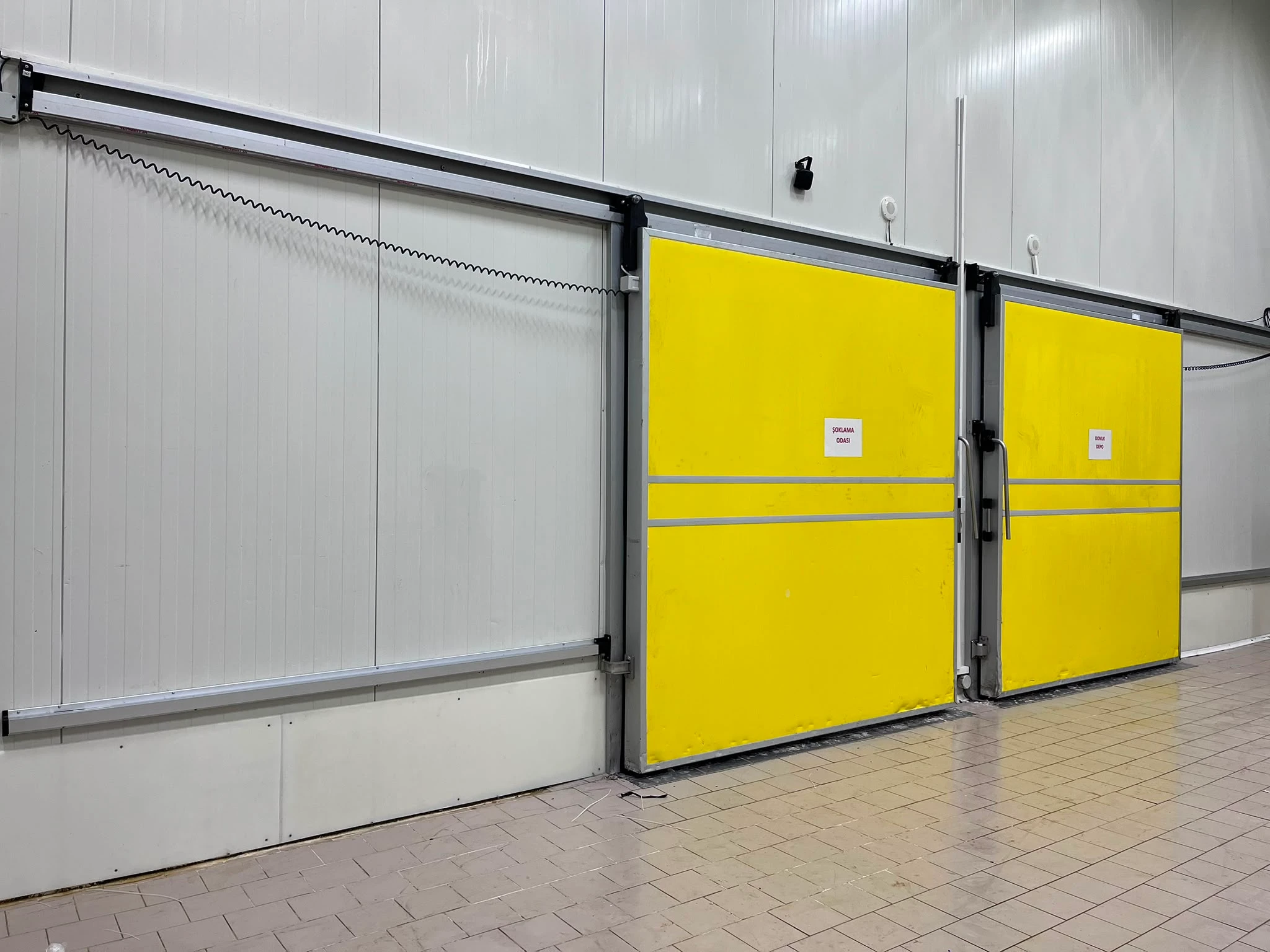 Yalıtımlı panel duvar üzerinde iki sarı sürgülü soğuk oda kapısı